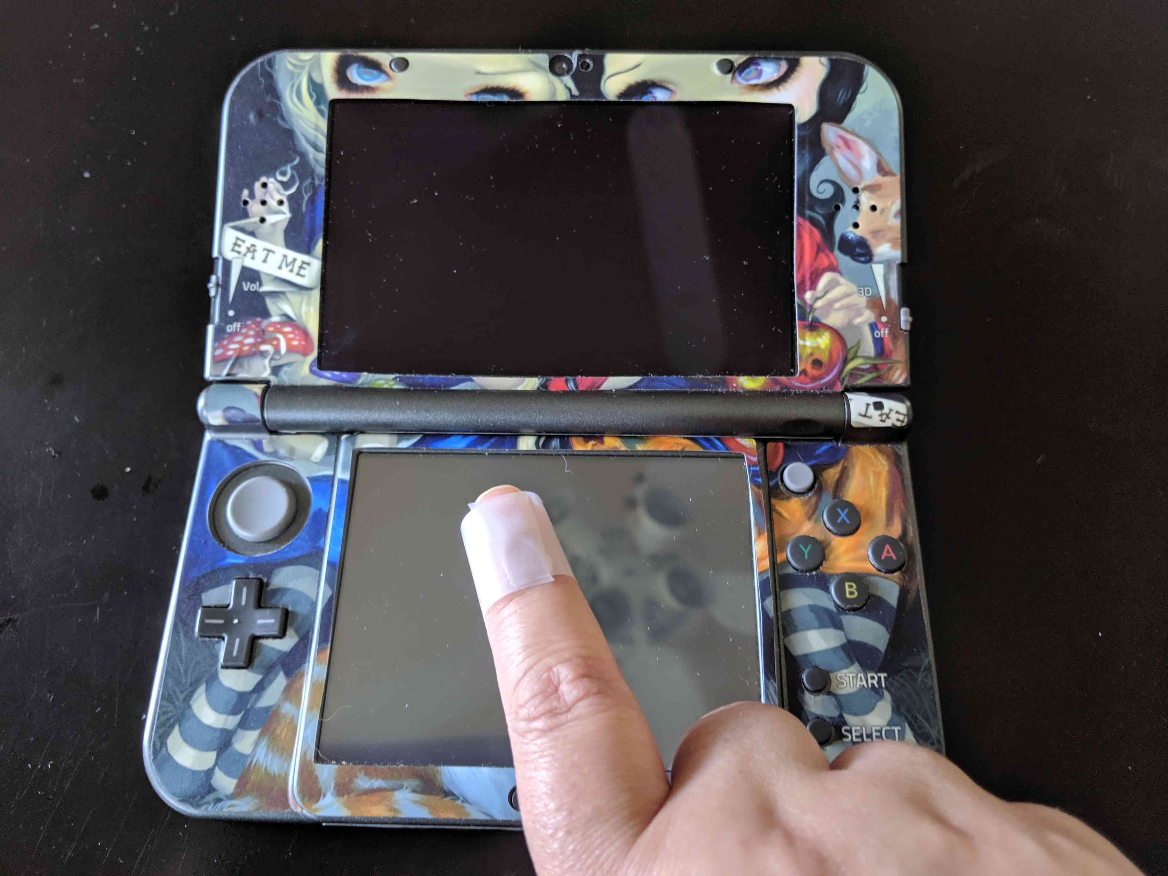 Рука на пыли на экране Nintendo 3DS с помощью скотча
