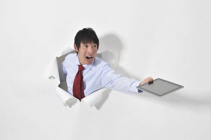 Бизнесмен пробивает белую стену, держа планшет (стоковое фото)