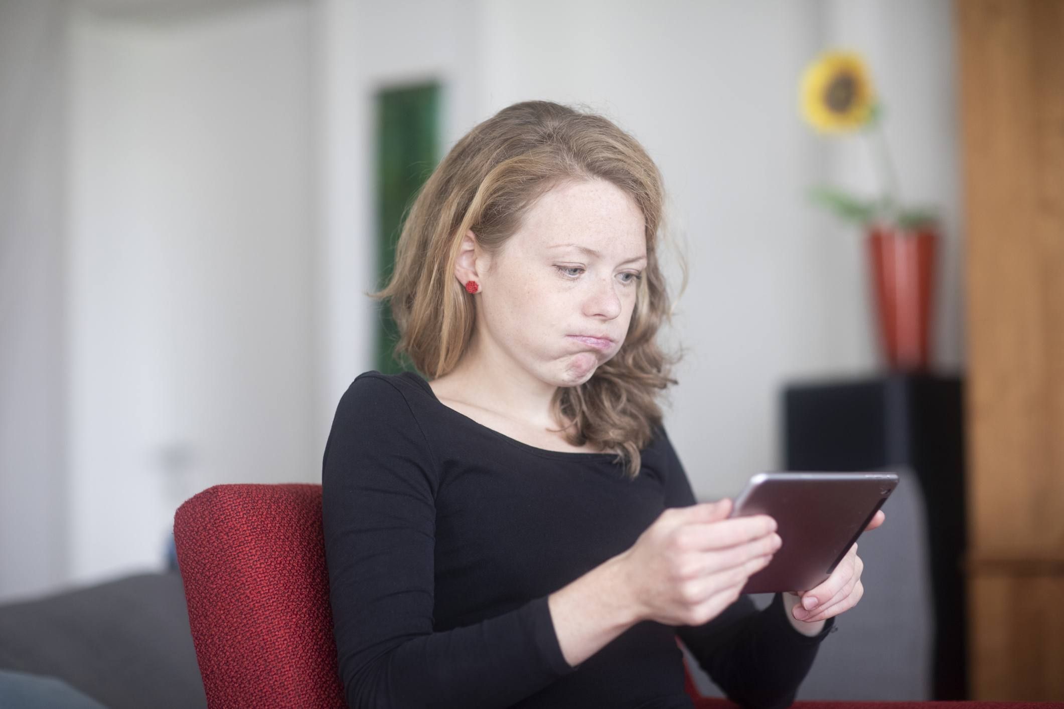 Женщина с помощью цифрового планшета, дует ее щеки