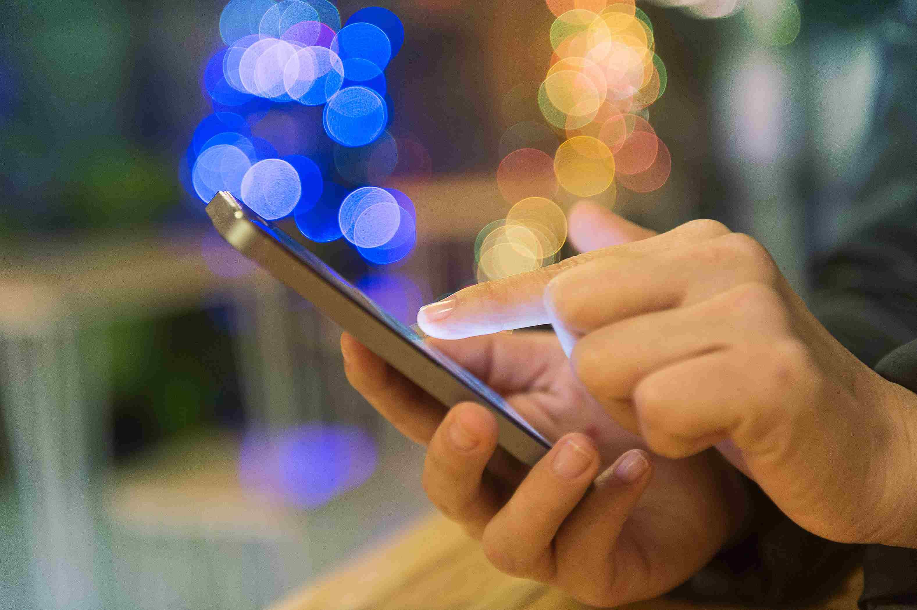 Выборочный фокус фрилансера Рука держит мобильный телефон для покупок в Интернете и мягких бликовых фильтров и перекрестного процесса