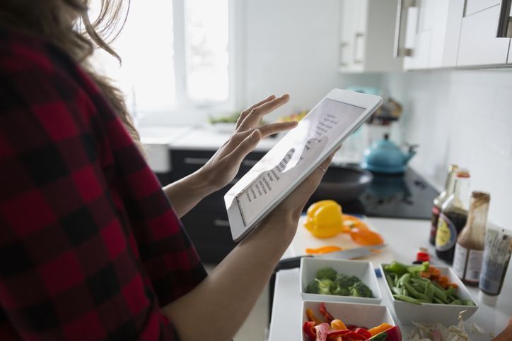 Женщина с цифровой планшет, приготовление пищи на кухне