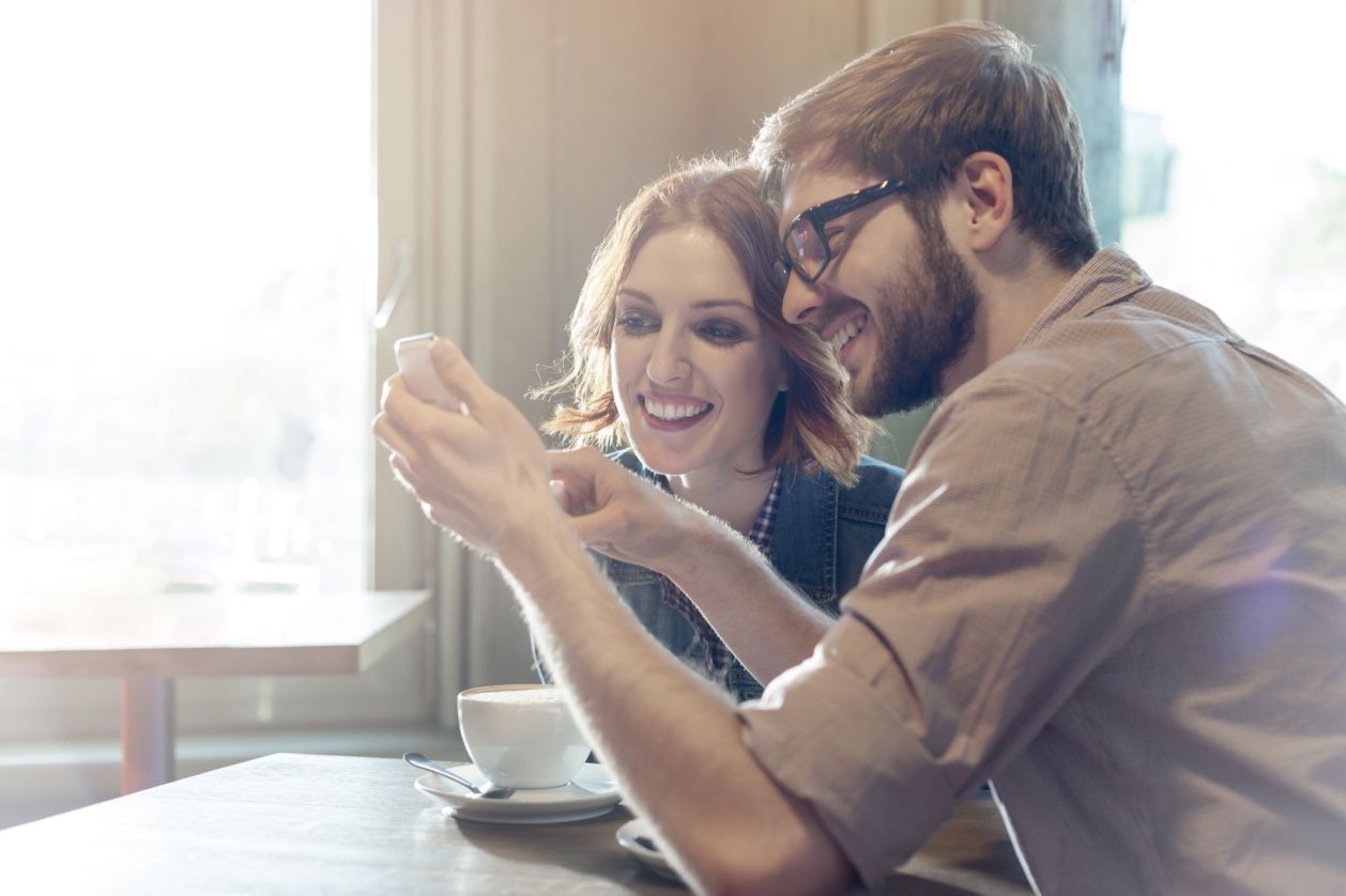 Мужчина и женщина, используя мобильный телефон в кафе.