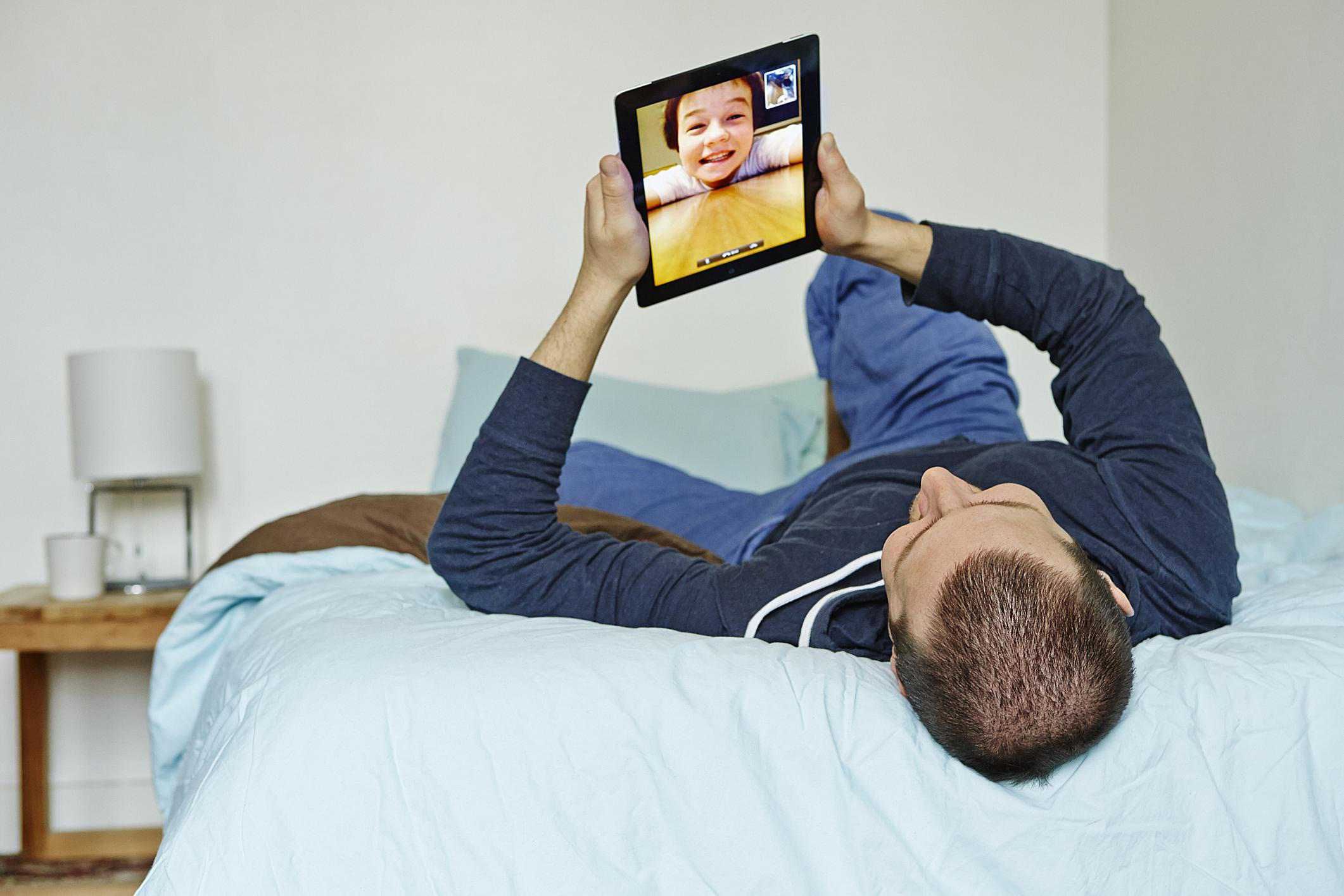 Человек использует iPad для видеочата с молодым парнем