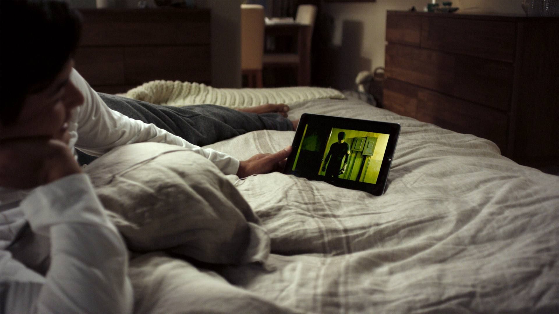 Женщина в постели смотрит на чудо's Daredevil and anime on Netflix on iPad