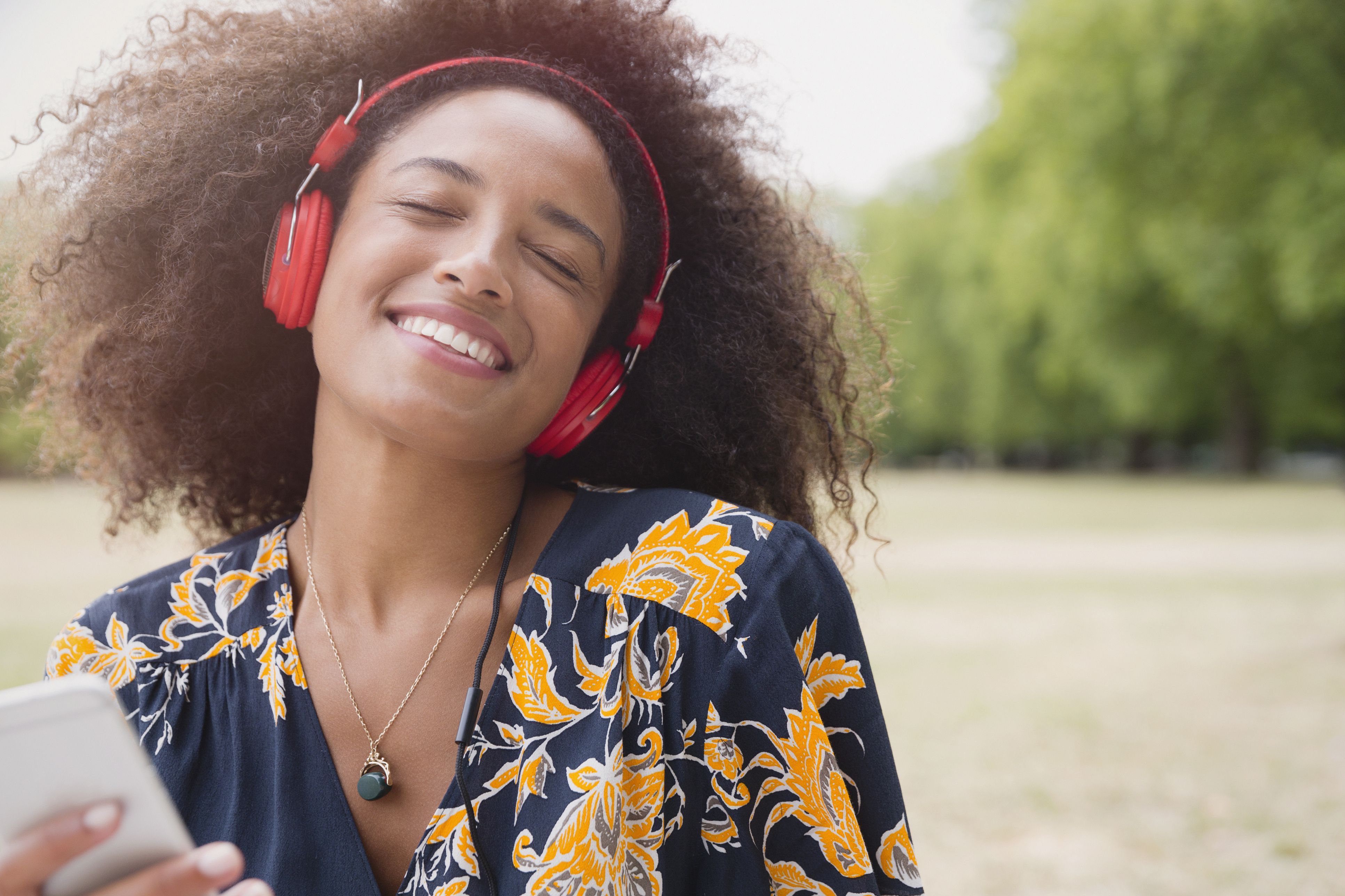 Восторженная женщина слушает музыку в наушниках и mp3-плеер в парке