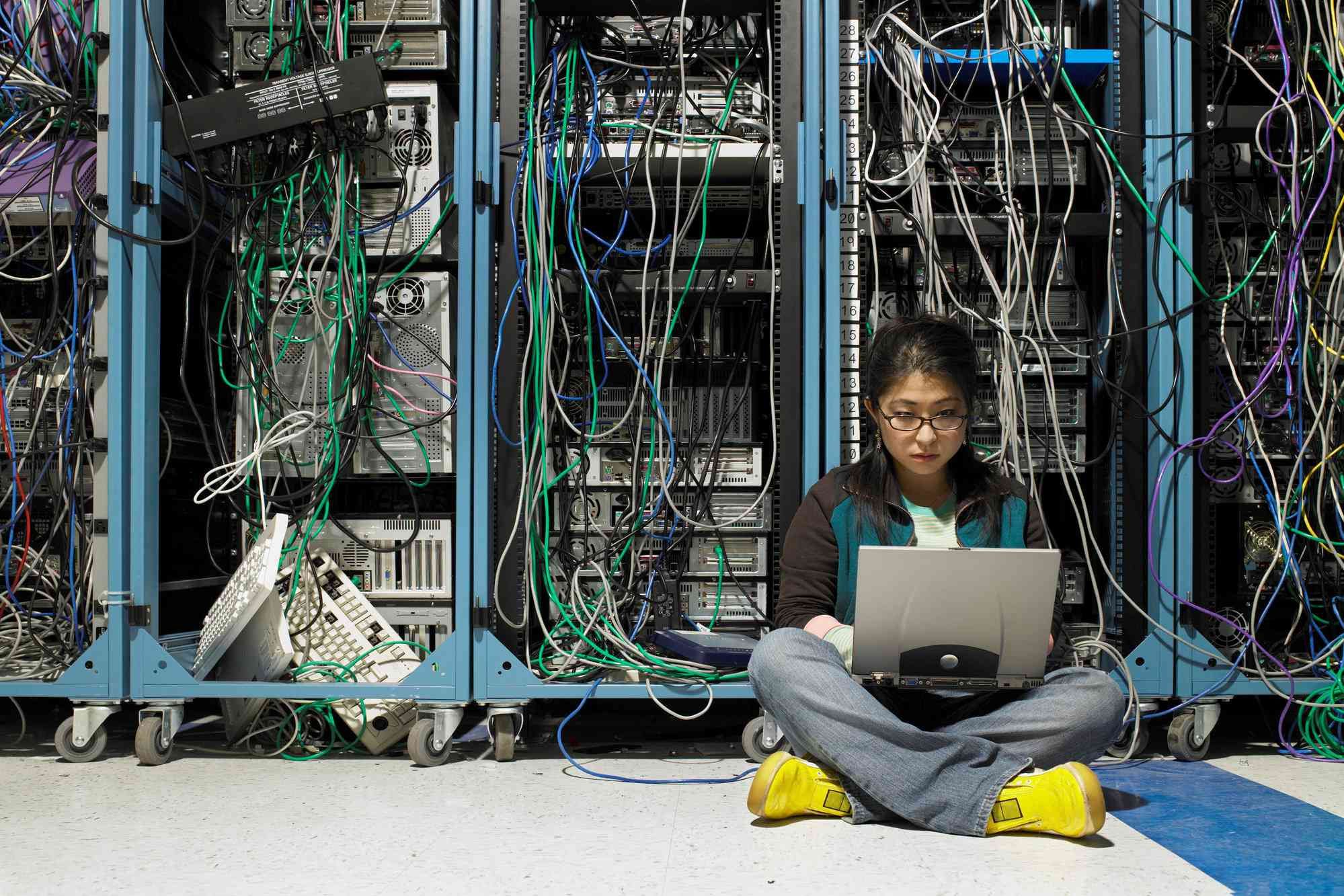 Молодая женщина, используя ноутбук в серверной комнате